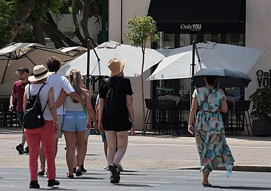 Tourists protect themselves from the sun in Malaga with umbrellas and hats on Sunday.