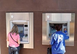 Two people withdraw money at a bank branch.