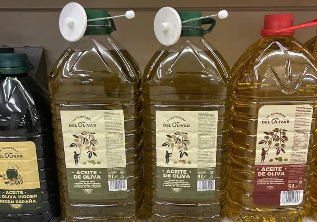 Security tags on bottles of olive oil on a supermarket shelf.