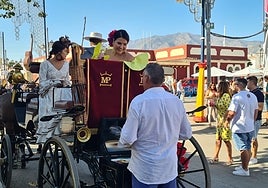 A woman dressed in a flamenco dress speaks to a man from a horse carraige during Fuengirola's feria.