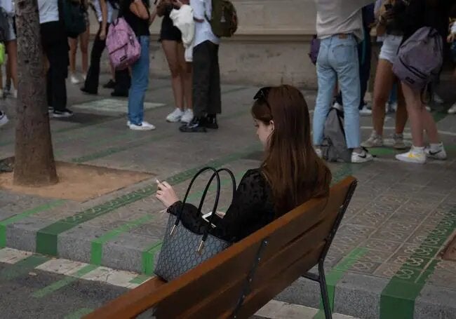 A woman smokes sitting on a bench outside a school in Barcelona