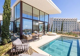 View of the terrace and swimming pool of one of the villas, with the apartment building in the background.