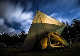 A happy camper resting body and mind in his tent under the stars.