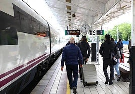 Passengers with their suitcases at a train station in Spain.