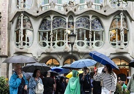 Tourists take shelter from the rain in the vicinity of the Casa Batlló on Passeig de Gràcia in Barcelona.