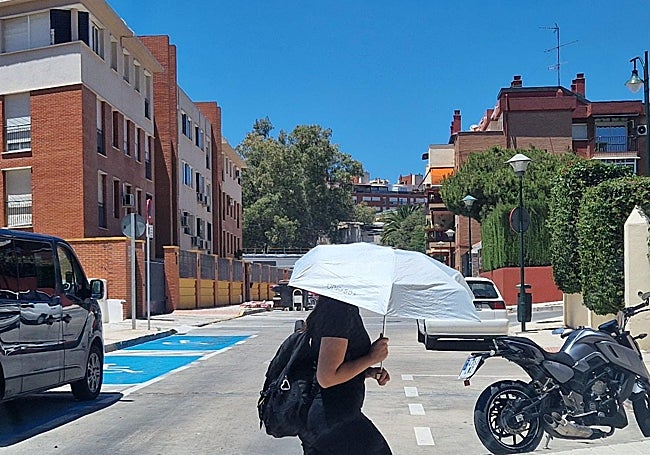 A woman takes shelter from the summer heat with a parasol.