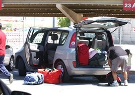 A family loads luggage into a rental car picked up at the airport.