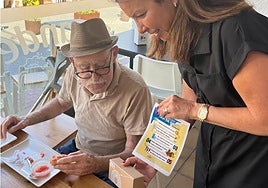 Councillor Lola Ramos hands out a fan and leaflet to a resident.