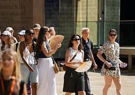Tourists stroll through the city armed with fans.