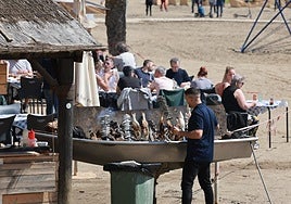 An espetero keeps an eye on the charcoal grill.