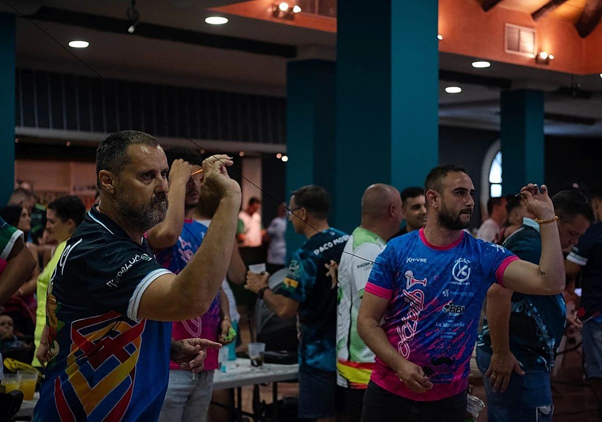 Imagen principal - Top, players at the Pizarra darts competition; bottom left, professional player Riky Pérez; bottom right, one of the dart boards in use. 