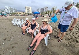 One of the volunteers pours water over Mercedes and others as they sit in front of the sea.