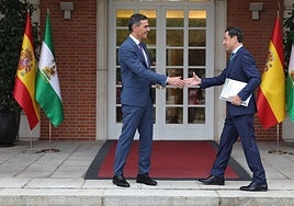 Pedro Sánchez receives the Andalusian president at the main entrance to La Moncloa palace.