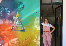 Artist Marta Bernad stands at the entrance of Artelier 21, next to a mural by Darko, an influential artist in Estepona's street art scene.