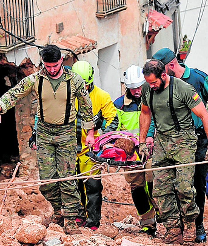 Imagen secundaria 2 - From top: A woman weeps in a devastated street in the Valencian town of Sedaví, rescuers in Mira in Cuenca (Castilla- La Mancha) and a person is evacuated in Letur (Castilla-La Mancha). 