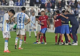 Malaga's Antoñito, left, rues missed chances as the Estepona players celebrate.