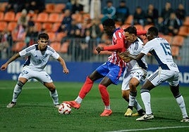 Three Marbella players attempt to win back the ball.