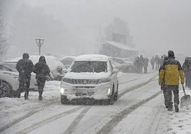 Tourists and local residents in Canfranc remove snow from their cars with shovels.