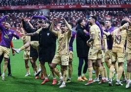 Malaga players celebrate the win with the travelling fans following the final whistle.