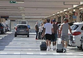 Tourists make their way through the airport car park.