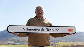 The mayor of Villanueva del Trabuco, Juan Luís Gallardo, holds a Mastercard poster with the name of the municipality.