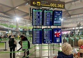 Passengers check their flights at an information panel at Malaga Airport.