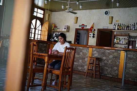 A woman drinks a soft drink at Jairo's bar, the only one in Bayubas de Abajo.