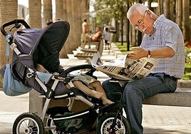 A citizen reads a regional newspaper while taking care of his grandson in an Andalusian park.