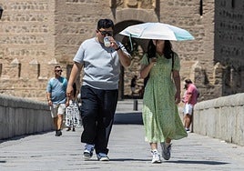 Tourists protect themselves from the sun during the heatwave in Toledo.