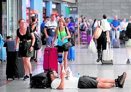 A passenger waits for his train lying on the floor at María Zambrano station in Malaga on Tuesday.