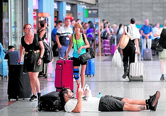 A passenger waits for his train lying on the floor at María Zambrano station in Malaga on Tuesday.