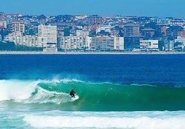 A surfer riding a wave at Somo beach, Cantabria.