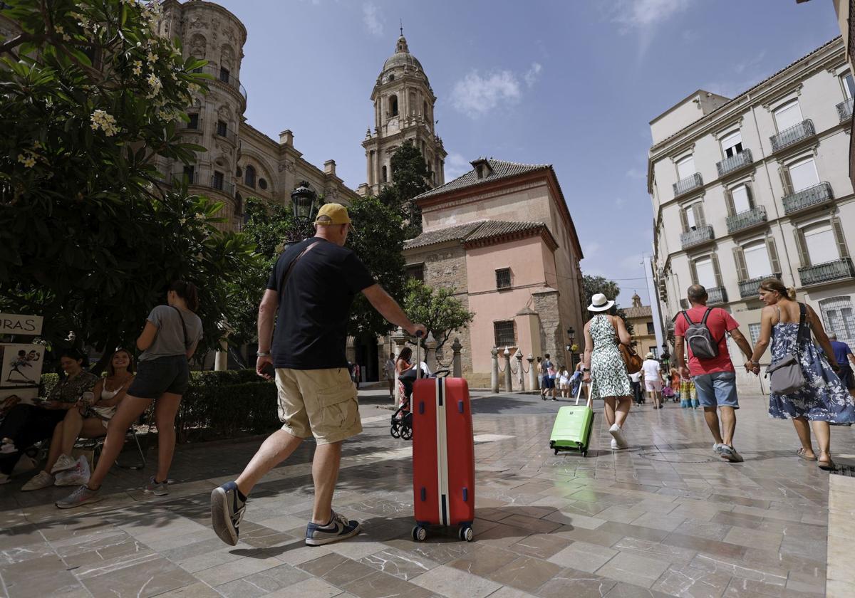 Tourists walk with their suitcases to their accommodation in Malaga.