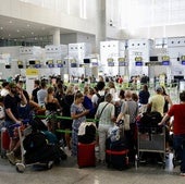 Passengers queue to check in their luggage.