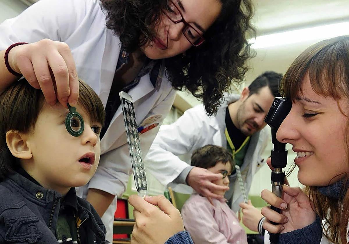 Two opticians carry out vision tests on a child at the Nuestra Señora de Atocha school in Murcia.
