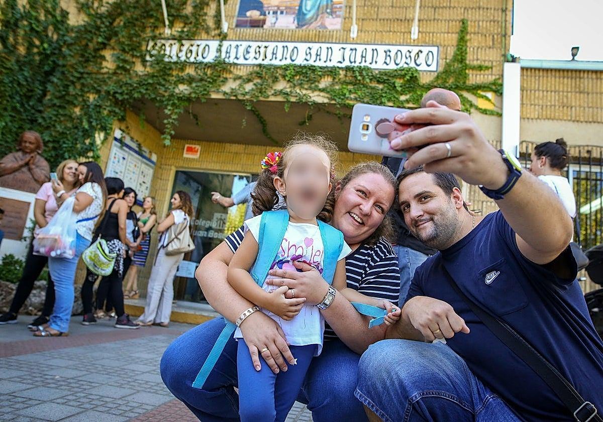 Parents take a selfie with their daughter at the school gates.