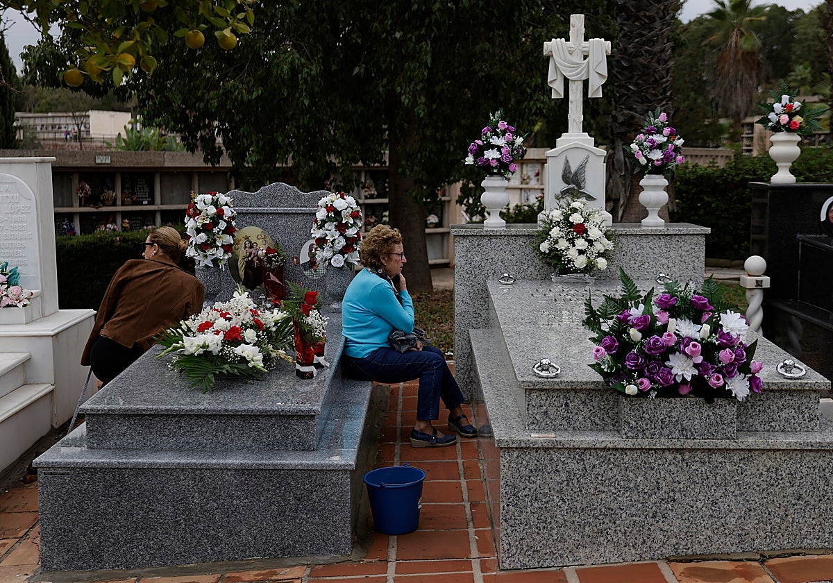 Two women keep vigil by their loved ones' graves at Malaga's San Gabriel cemetery.