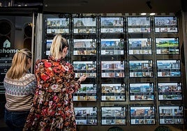 Two women look at property offers in a real estate agency.