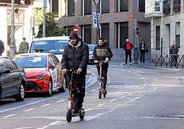 Two electric scooter riders make their way through Valladolid city centre.
