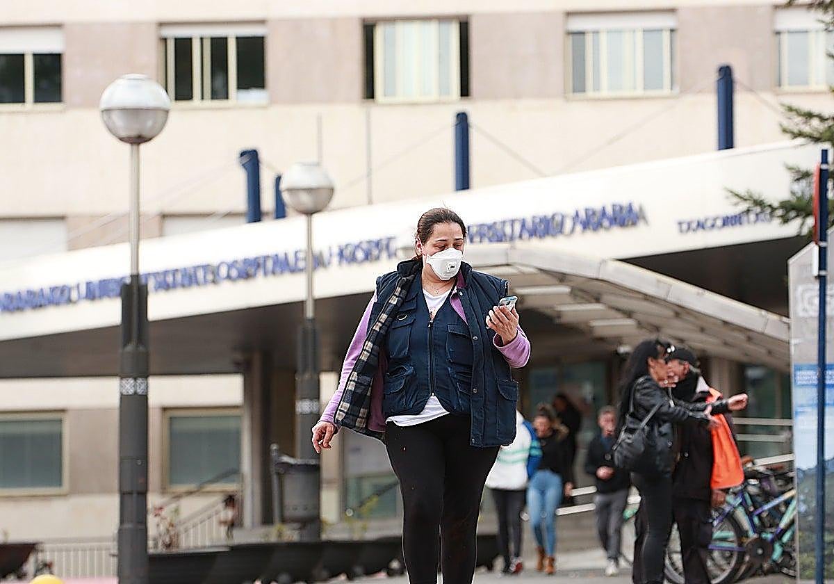 A woman leaves the hospital emergency room wearing a mask.