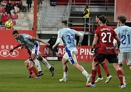 Malaga's Einar Galilea wins an aerial duel during Monday's match.