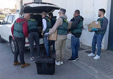 Guardia Civil investigators take boxes with material seized in the search.