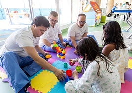 Three volunteers from the Nena Paine foundation playing with two girls in Malaga's Materno Infantil hospital.