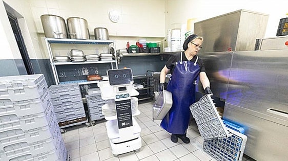 One of the professionals who tends the buffet at the Gran Hotel Luna gives Electra the dirty dishes.