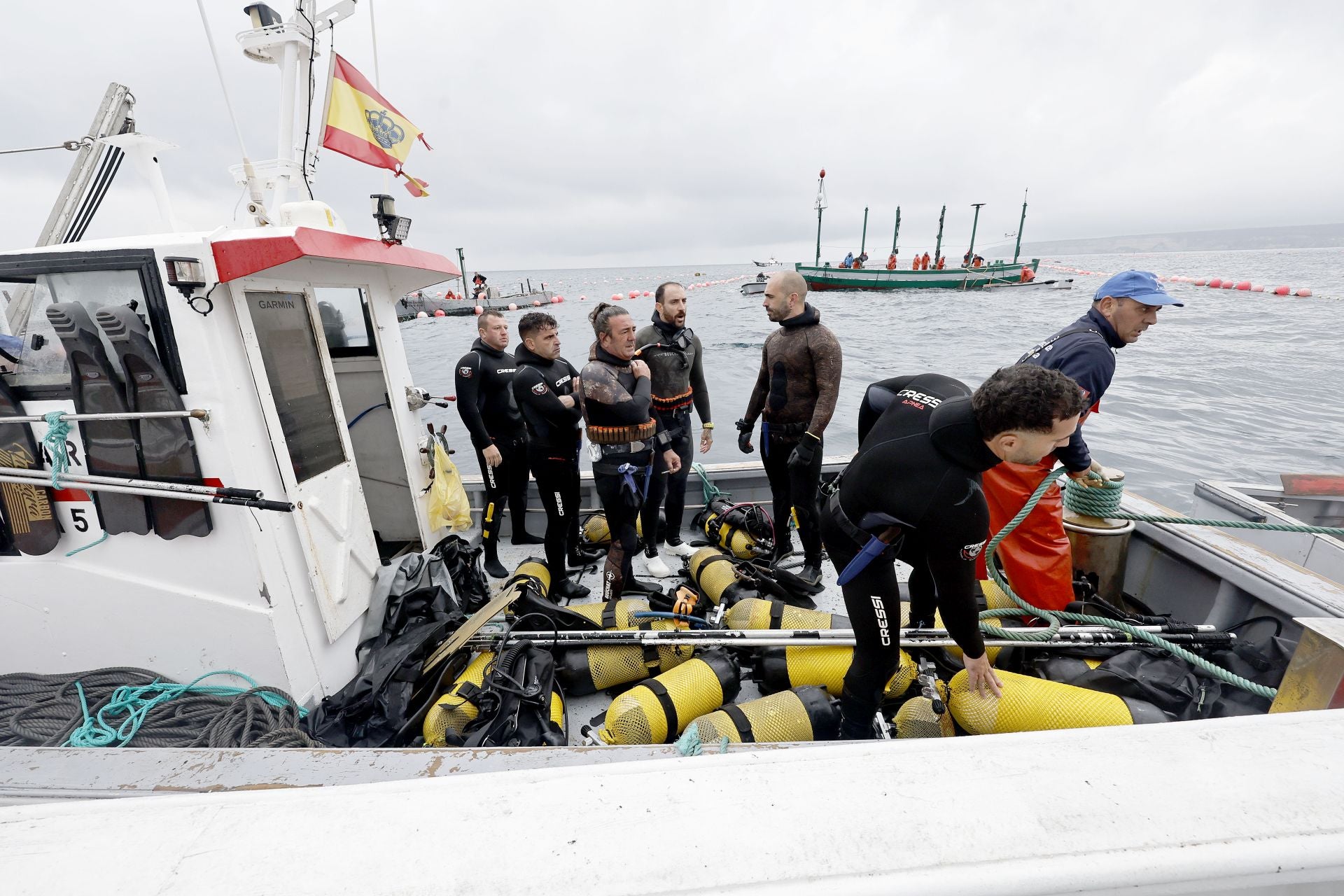 Imagen principal - Top, the divers prepare to gauge the fish before directing them to the ‘copo’ net; Below, one of the vessels that forms part of the almadraba fleet and a crew member from the freezer ship used to transport the tuna for sale