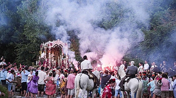 Participants from Seville cross a river at the famous Vado de Quema