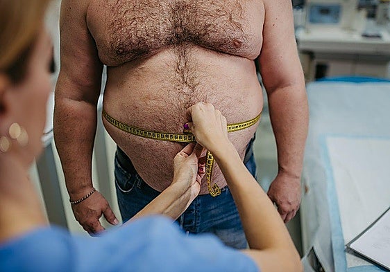 A specialist measures the waist of a patient with obesity.