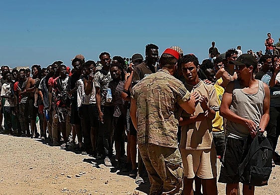 Migrants who crossed from Morocco into Ceuta are queuing to receive water from the Spanish military.