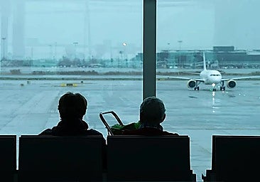 Two people sitting inside an airport.