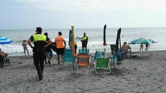 Police officers remove items from a beach in Torrox.